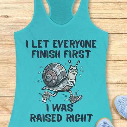Turquoise tank top with a snail graphic and text I let everyone finish first I was raised right, on a wooden surface