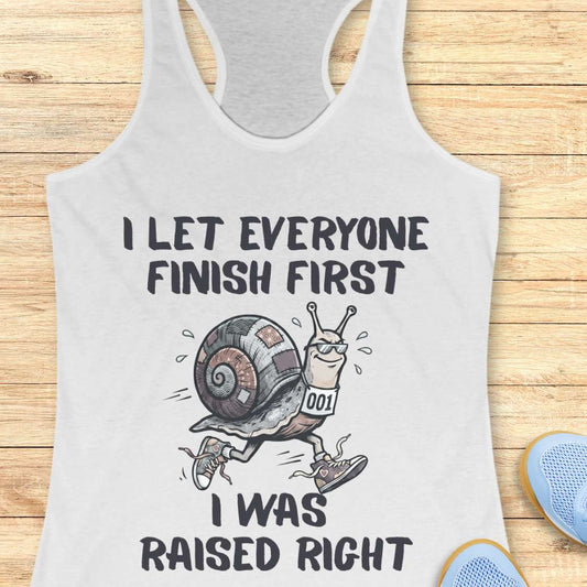 white tank top with a snail graphic and text - I let everyone finish first I was raised right,  on a wooden surface