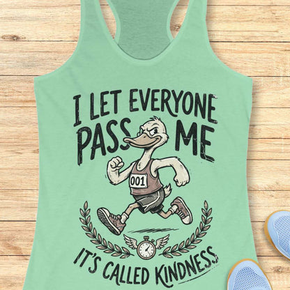 Mint green tank top with cartoon character and text I let everyone pass me, it's called kindness, on a wooden surface