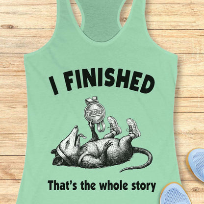 mint tank top with graphic of a rat and text 'I FINISHED That's the whole story' on a wooden surface.