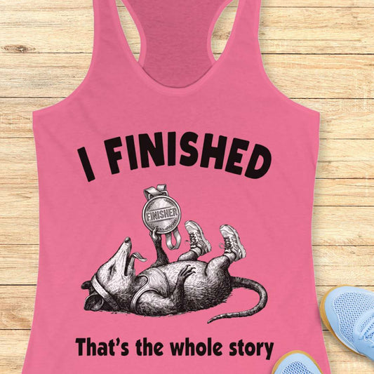 Pink tank top with graphic of a rat and text 'I FINISHED That's the whole story' on a wooden surface.