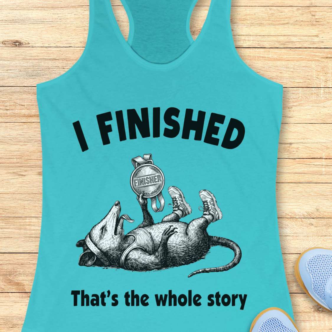 blue tank top with graphic of a rat and text 'I FINISHED That's the whole story' on a wooden surface.