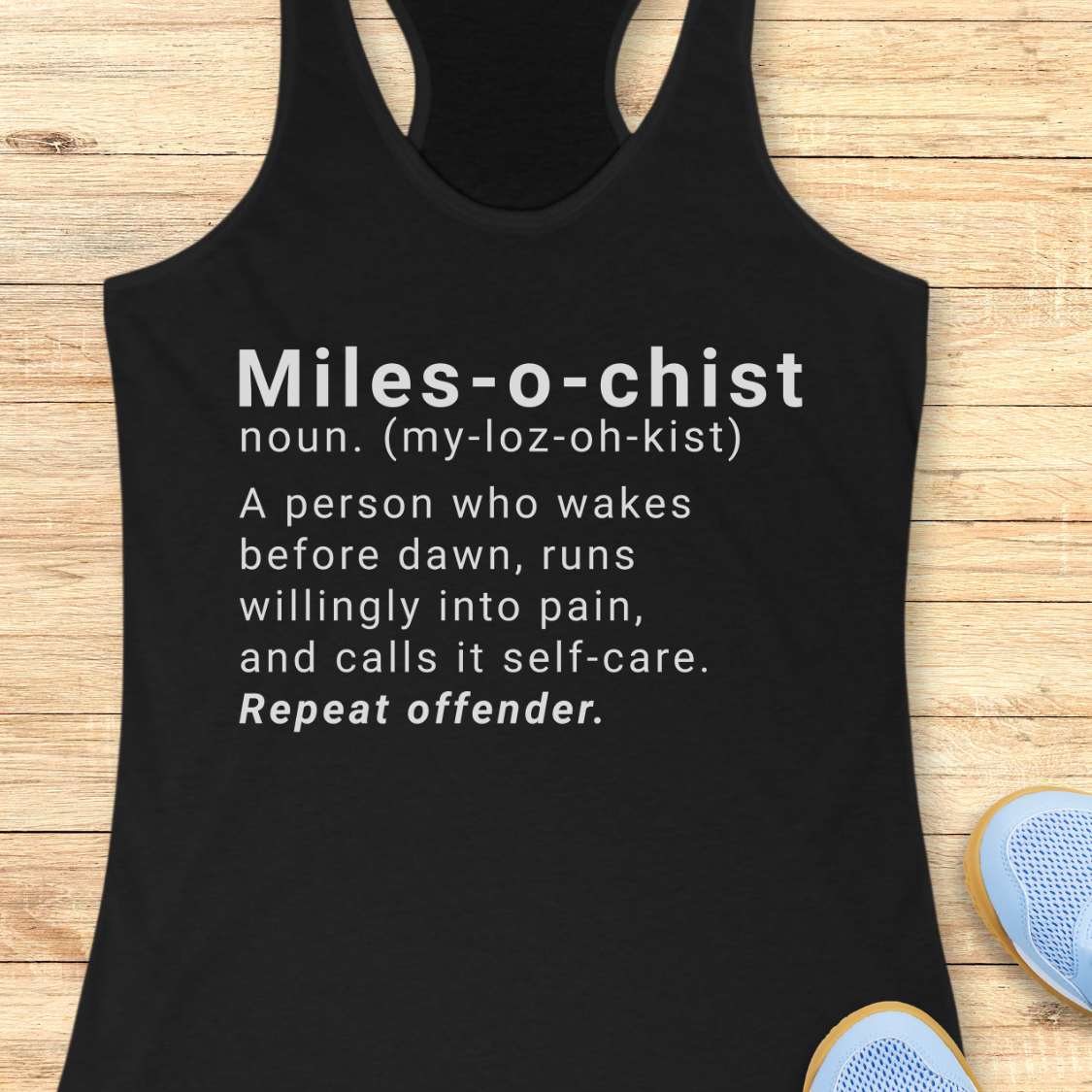 Black tank top with humorous definition text on a wooden surface