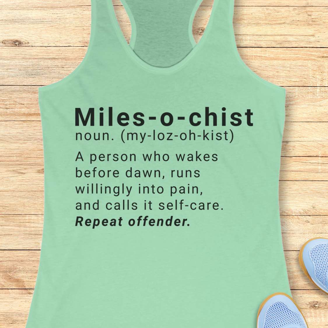 Green tank top with humorous definition text on a wooden surface