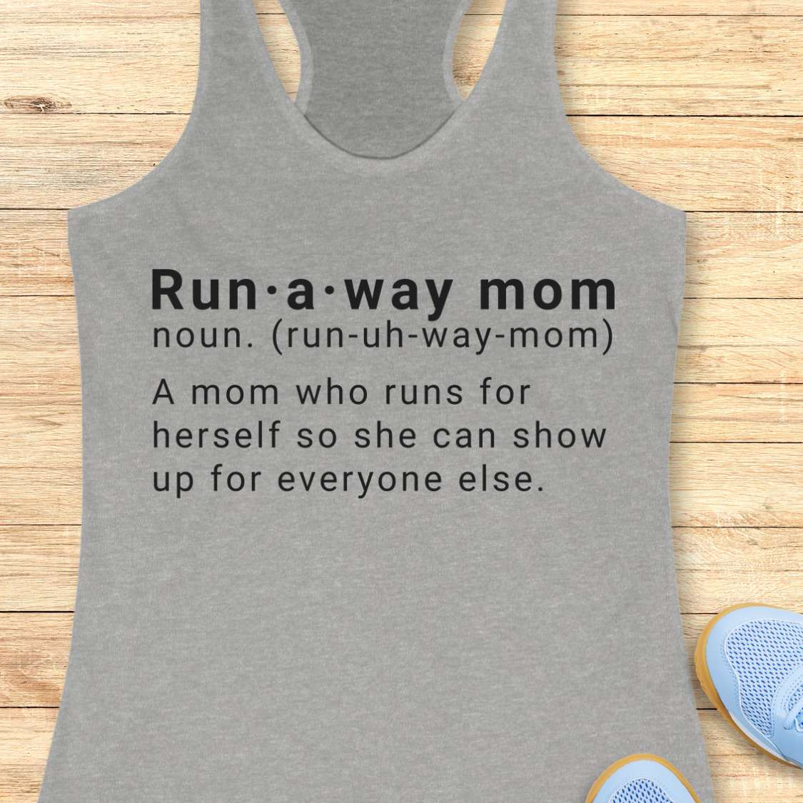 Gray tank top with dictionary definition of run a way mom text on a wooden surface