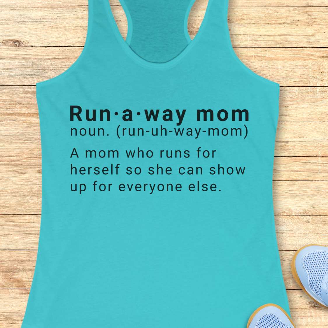 Turquoise tank top with dictionary definition of run a way mom text on a wooden surface