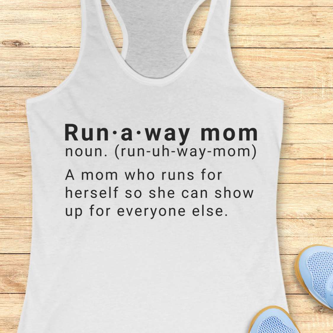 white tank top with dictionary definition of run a way mom text on a wooden surface
