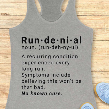 Gray tank top with humorous definition text  of run de ni al  on a wooden surface