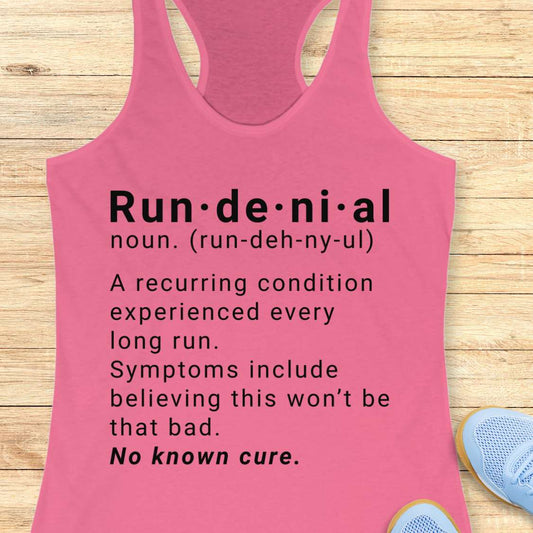 Pink tank top with humorous definition text of run de ni al on a wooden surface