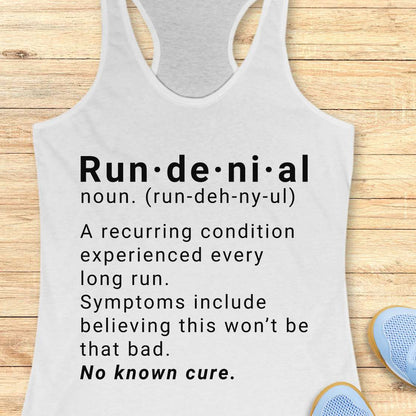 white tank top with humorous definition text  of run de ni al  on a wooden surface