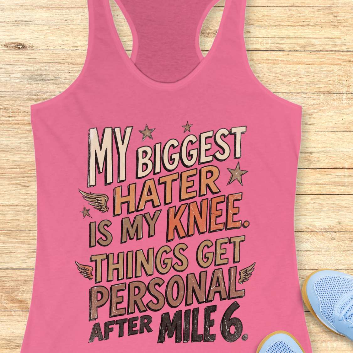 Pink tank top with humorous text on a wooden surface