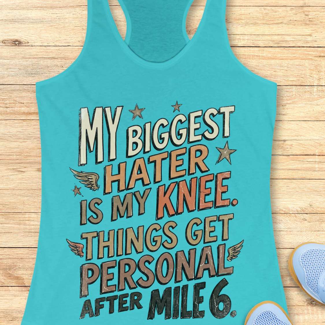 Turquoise tank top with motivational text on a wooden surface