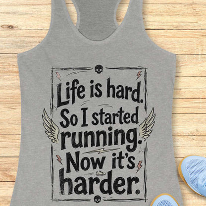 Gray tank top with a text - life is hard. So I started running. Now it's harder on a wooden surface