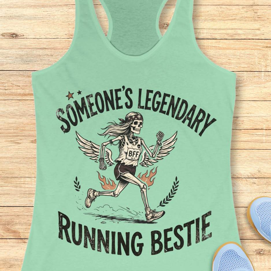 Mint green tank top with skeleton design and text someone's legendary running bestie on a wooden surface