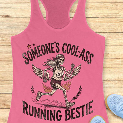 Pink tank top with skeleton graphic and text someone's cool-ass running bestie on a wooden surface