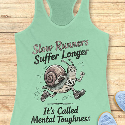 Mint green tank top with a snail graphic and text on a wooden surface