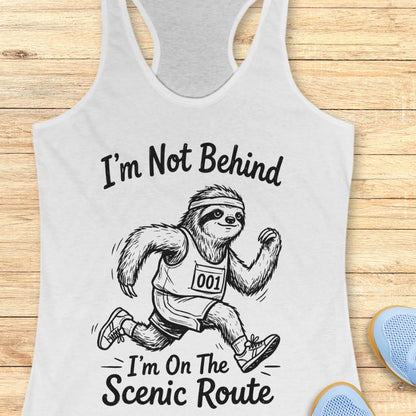 white tank top with a sloth running graphic and text I'm not behind, I'm on the scenic rout on a wooden surface
