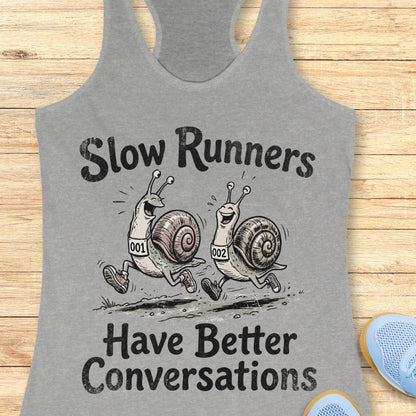 Gray tank top with snail design and text 'Slow Runners Have Better Conversations' on a wooden surface.