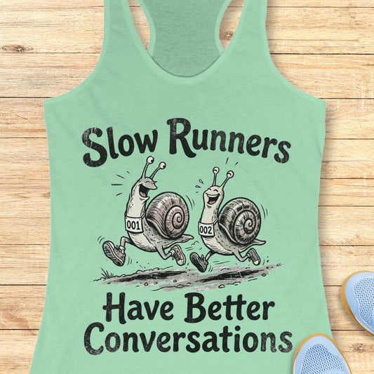 Light green tank top with snail graphic and text slow runners have better conversations on a wooden surface