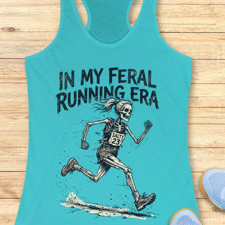 Turquoise tank top with skeleton running graphic and text 'In My Feral Running Era' on a wooden surface.