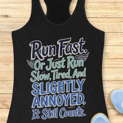 Black tank top with humorous text design "Run fast. Or just run slow, tired, and slightly annoyed. It still counts." on a wooden surface
