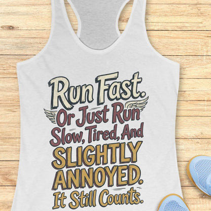 white tank top with humorous text "Run fast. Or just run slow, tired, and slightly annoyed. It still counts." design on a wooden surface