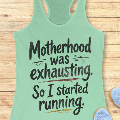 Light green tank top with humorous text motherhood was exhausting. So I started running. on a wooden surface
