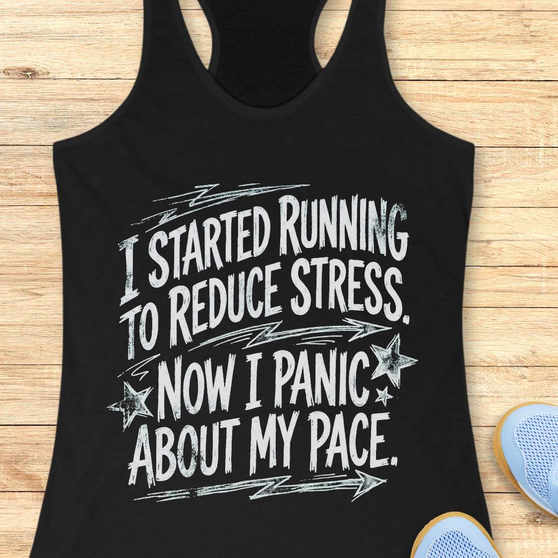 Black tank top with humorous running text I started running to reduce stress. Now I panic about my pace.  on a wooden surface