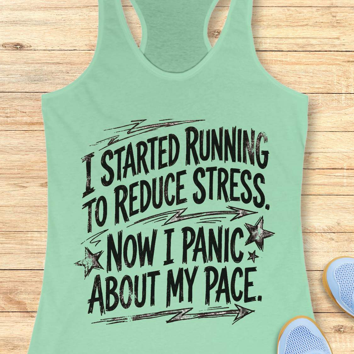 Mint green tank top with humorous running text I started running to reduce stress. Now I panic about my pace.  on a wooden surface