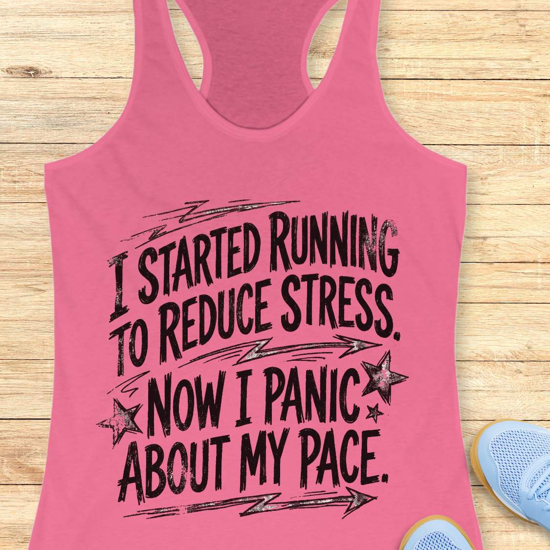 Pink tank top with humorous running text I started running to reduce stress. Now I panic about my pace.  on a wooden surface