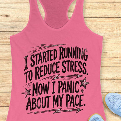 Pink tank top with humorous running text I started running to reduce stress. Now I panic about my pace.  on a wooden surface