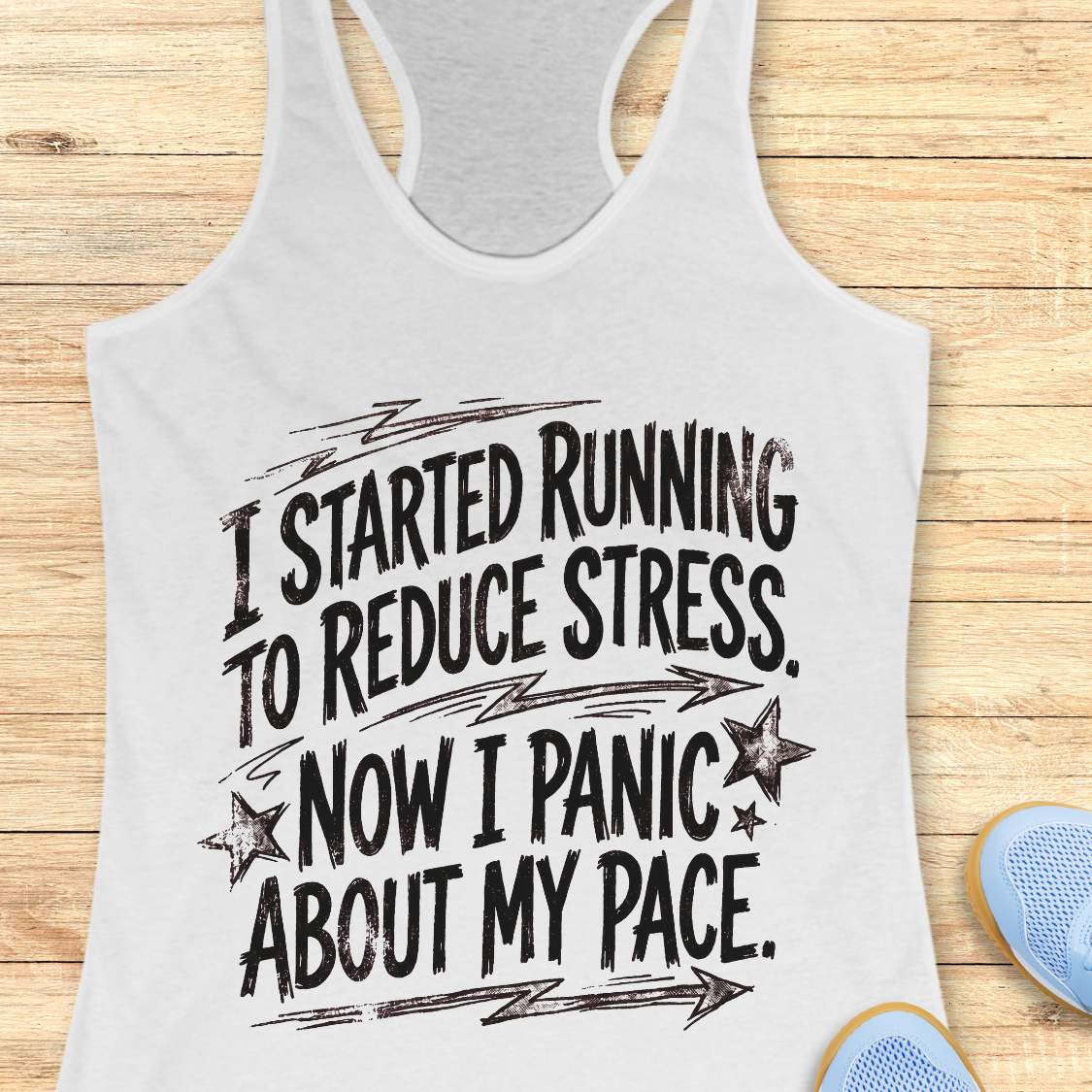 white tank top with humorous running text I started running to reduce stress. Now I panic about my pace.  on a wooden surface