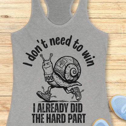 grey tank top with an image of  snail and text - I don't need to win I already did the hard part, on a wooden background