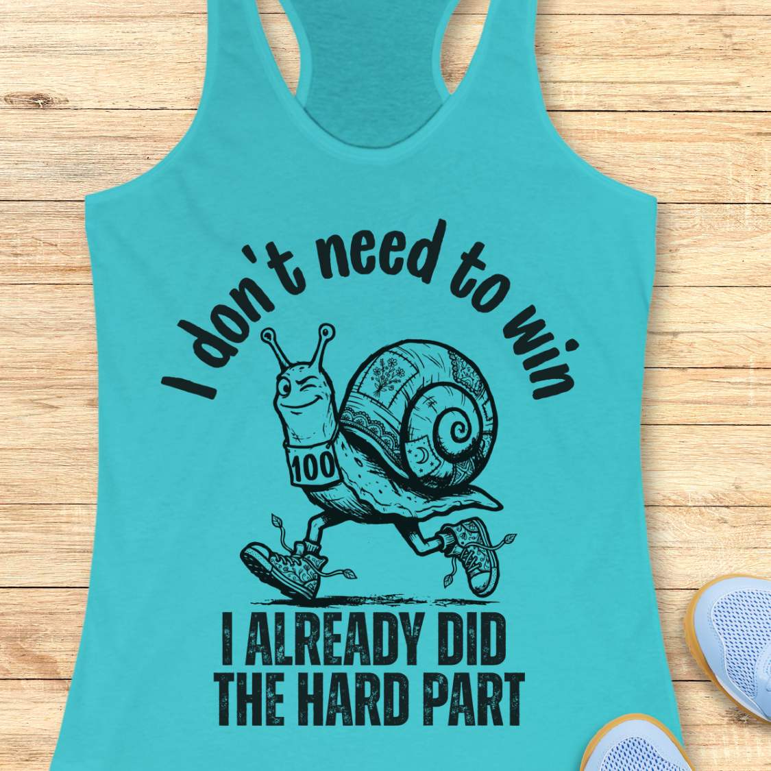 blue tank top with an image of  snail and text - I don't need to win I already did the hard part, on a wooden background