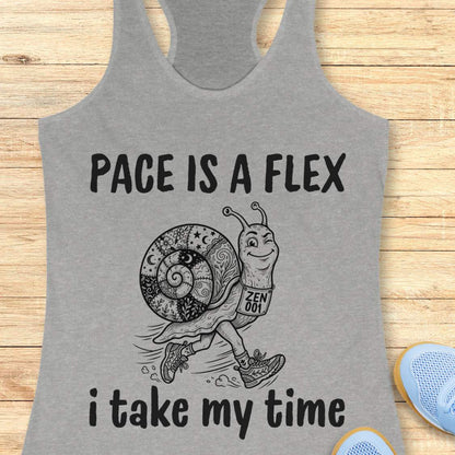 Gray tank top with a snail graphic and text pace is a flex , i take my time, on a wooden surface