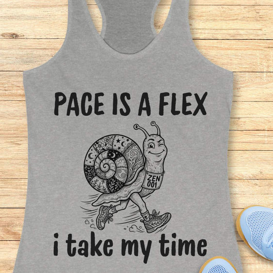 Gray tank top with a snail graphic and text pace is a flex , i take my time, on a wooden surface