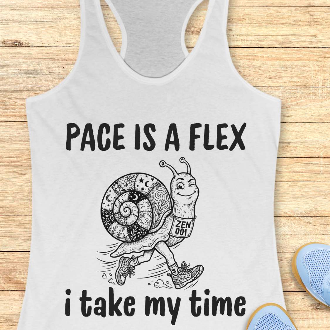 white tank top with a snail graphic and text pace is a flex , i take my time, on a wooden surface