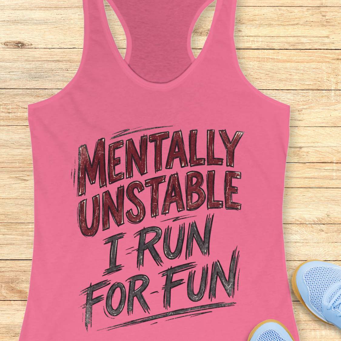 Pink tank top with text 'Mentally Unstable I Run For Fun' on a wooden surface.
