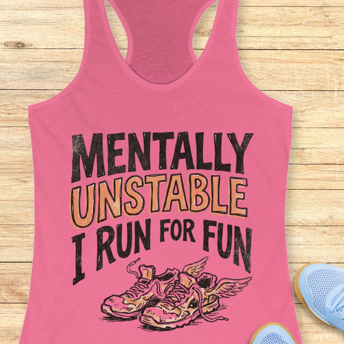 Pink tank top with 'Mentally Unstable I Run For Fun' text and running shoes graphic on a wooden surface.