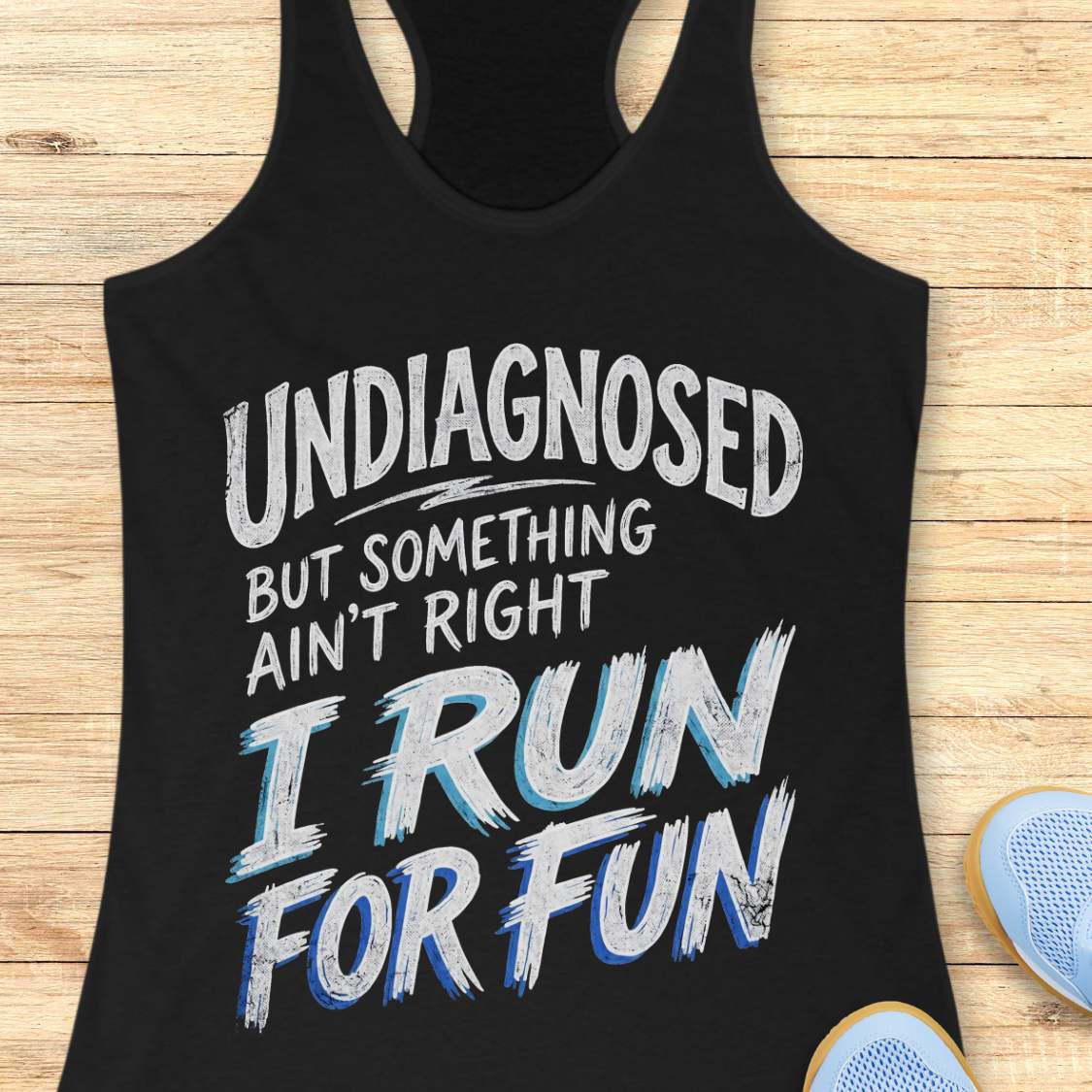 Black tank top with humorous text undiagnosed but something ain't right, I run for fun,  on a wooden surface