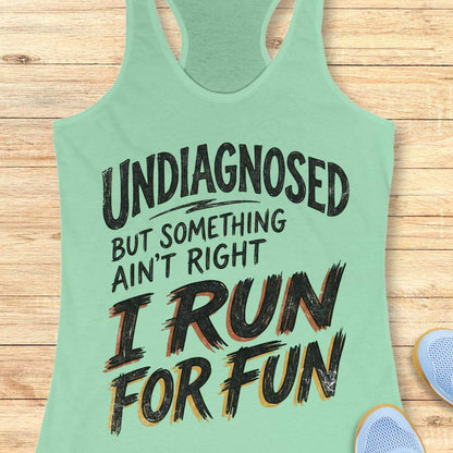 Light green tank top with humorous text undiagnosed but something ain't right, I run for fun, on a wooden surface