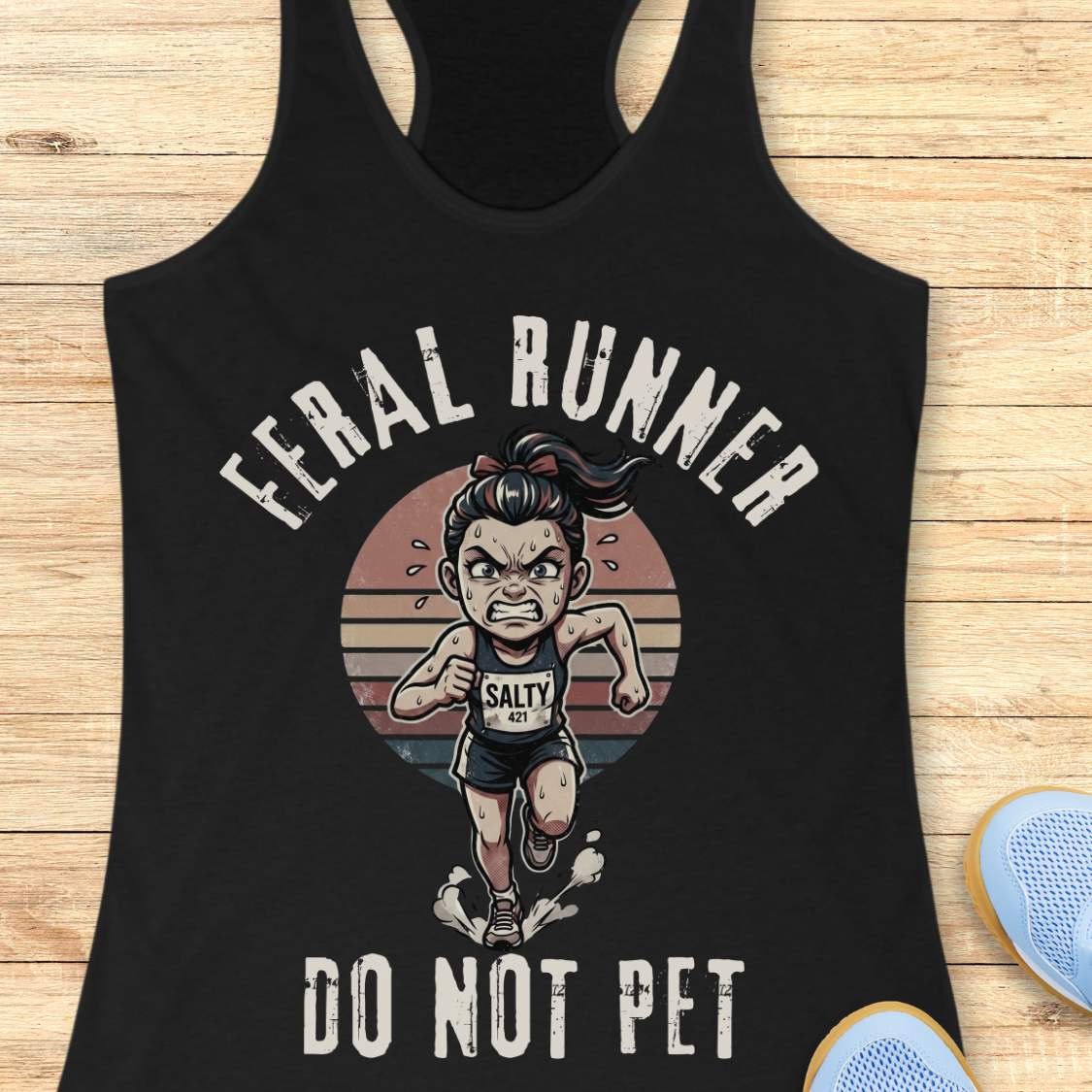 Black tank top with graphic design of a running person and text feral runner do not pet on a wooden surface