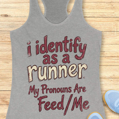 Gray tank top with text 'i identify as a runner My Pronouns Are Feed/Me' on a wooden surface