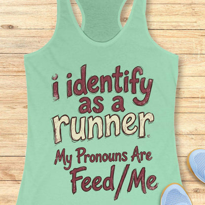 Mint green tank top with text 'i identify as a runner My Pronouns Are Feed/Me' on a wooden surface