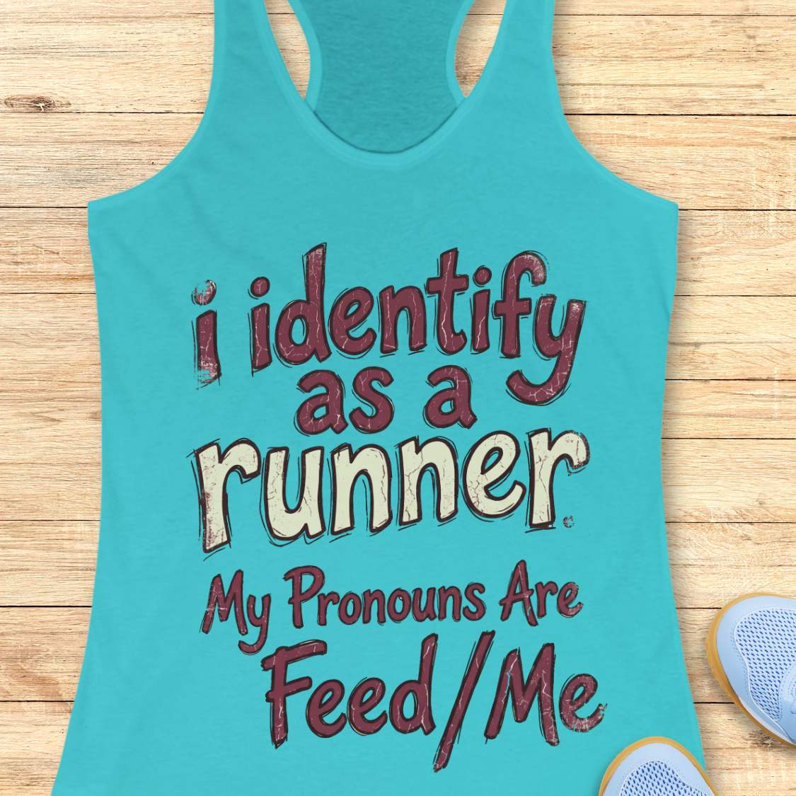 Turquoise tank top with text 'i identify as a runner My Pronouns Are Feed/Me' on a wooden surface