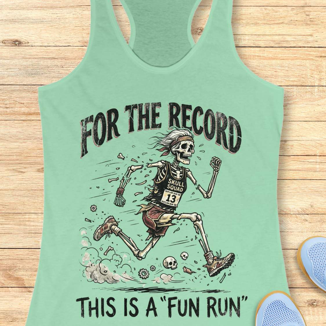 mint tank top with skeleton graphic and text 'For the Record, This is a Fun Run' on a wooden surface.