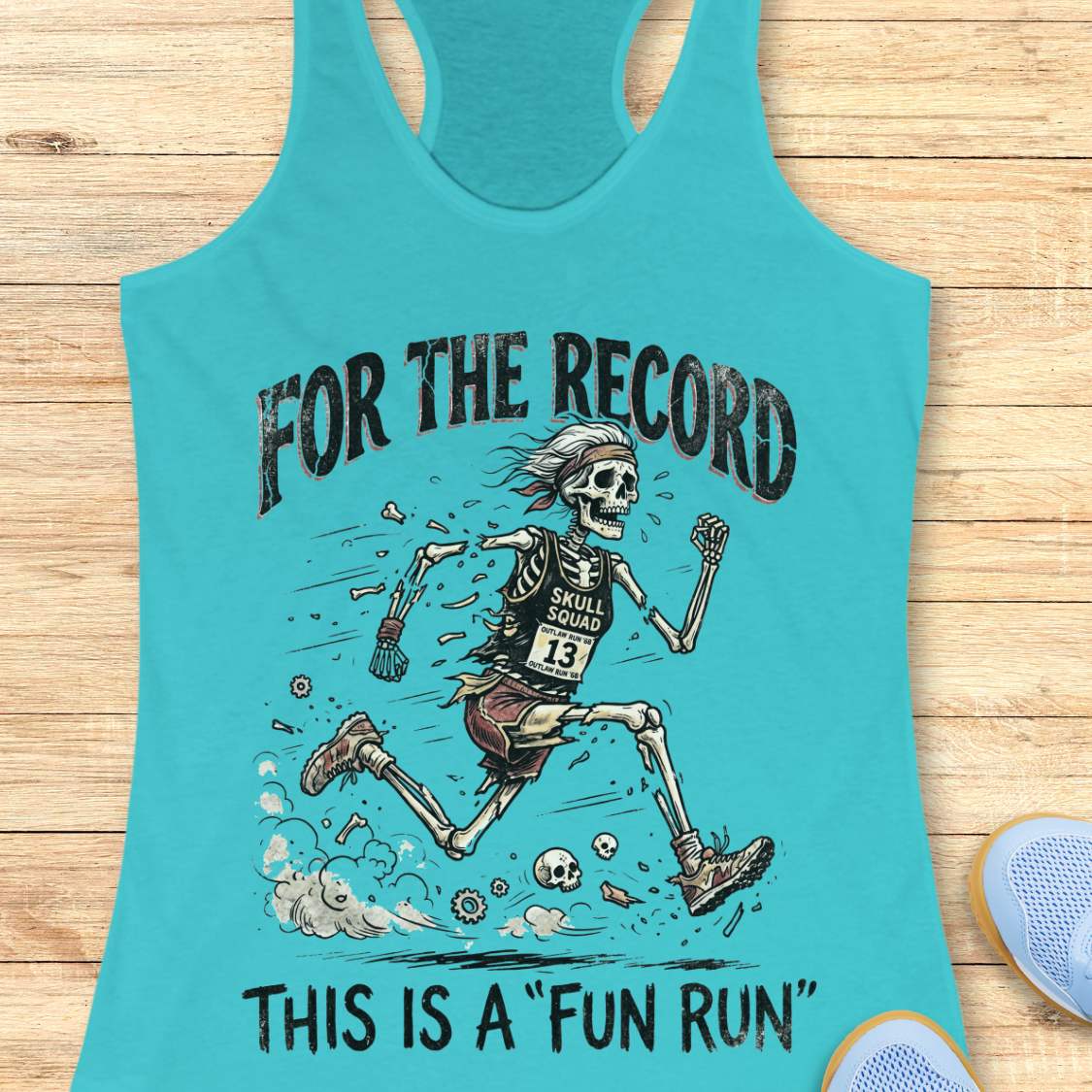 Turquoise tank top with skeleton graphic and text 'For the Record, This is a Fun Run' on a wooden surface.