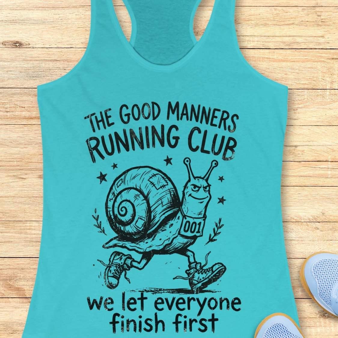 Turquoise tank top with a snail graphic and text The good manners running club, we let everyone finish first, on a wooden surface