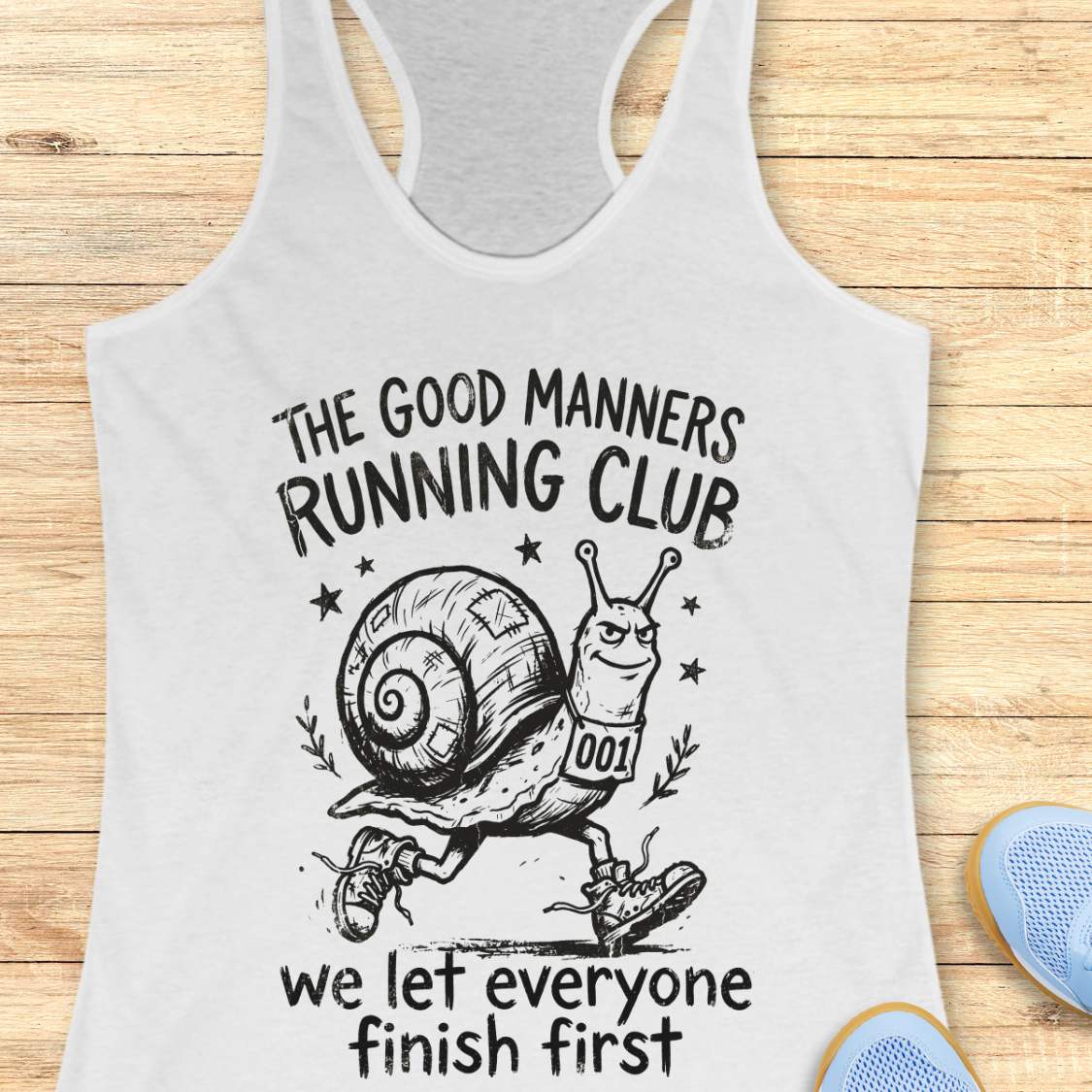 white tank top with a snail graphic and text The good manners running club, we let everyone finish first, on a wooden surface