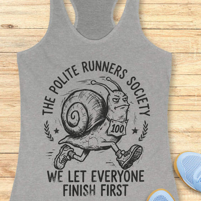 Gray tank top with a snail graphic and text 'The Polite Runners Society' on a wooden surface